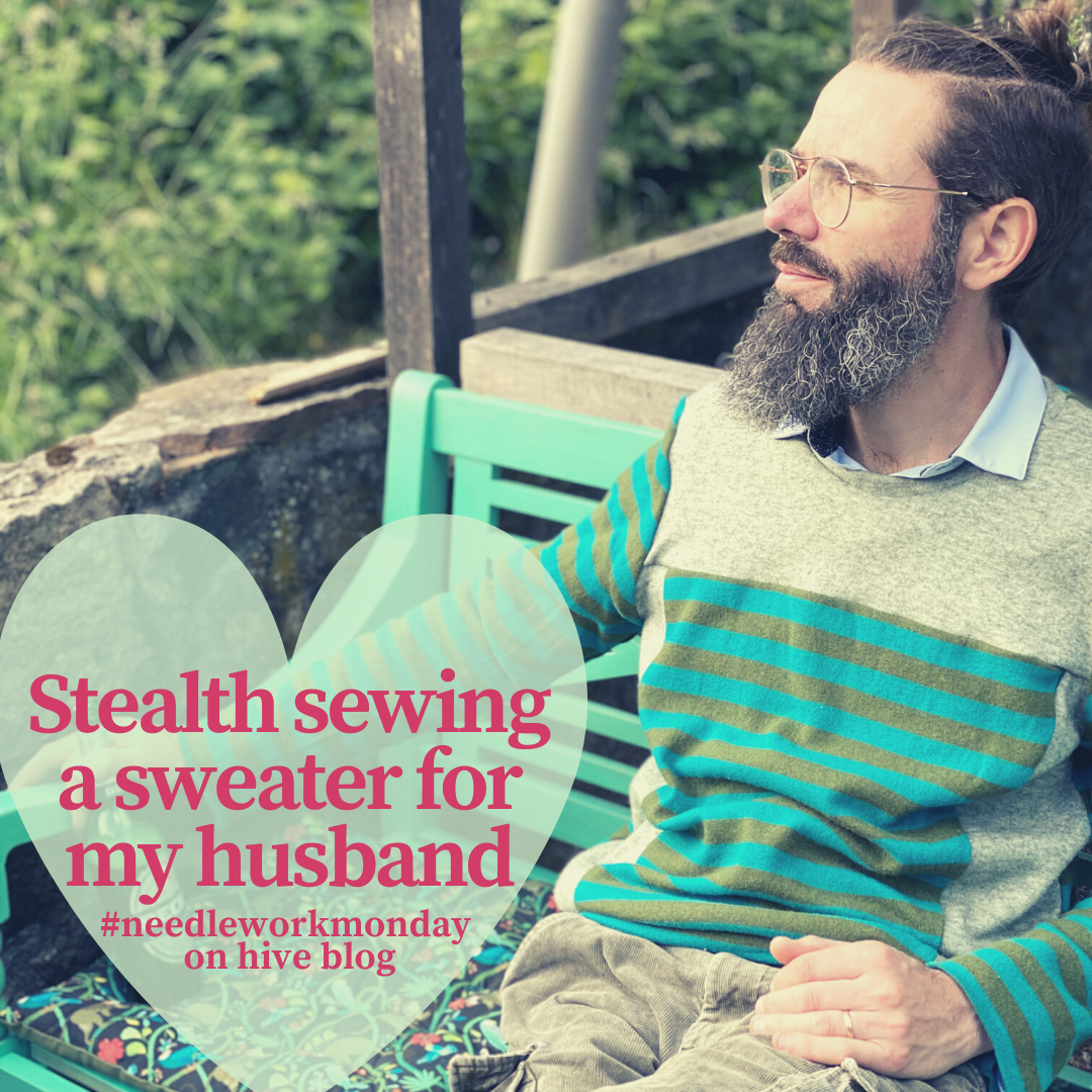 a bearded man wearing a handmade striped sweater in a garden